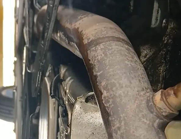 Engine oil leaking from the valve cover onto a hot exhaust manifold, causing a burning smell and fire hazard.