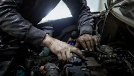 A mechanic disassembling an engine, showing why labor drives up the valve cover gasket replacement cost.
