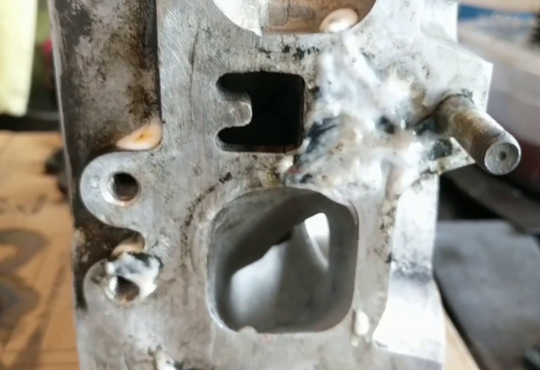 Professional mechanic using gasket remover on a cylinder head.