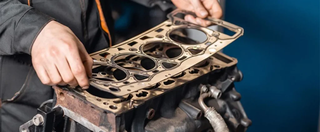 Professional mechanic installing a new head gasket repair kit on a heavy-duty commercial engine.