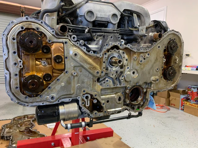 Mechanic scraping failed high temp silicone sealant from an engine block.