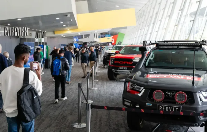 A busy expo hall at the Australian Auto Aftermarket Expo 2026, showing heavy-duty truck engines on display and industrial B2B visitors networking