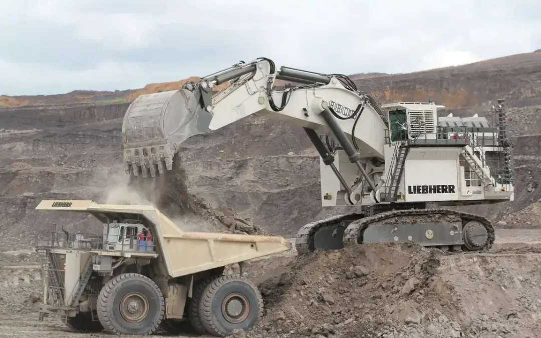 Massive Liebherr R9800 mining excavator loading a 360-ton haul truck in an open-pit mine during sunrise, showing the machine’s enormous bucket and hydraulic system.