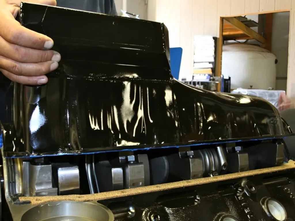 A professional diesel mechanic carefully installing an oil pan gasket on the lower block of a heavy-duty engine using a precision torque wrench