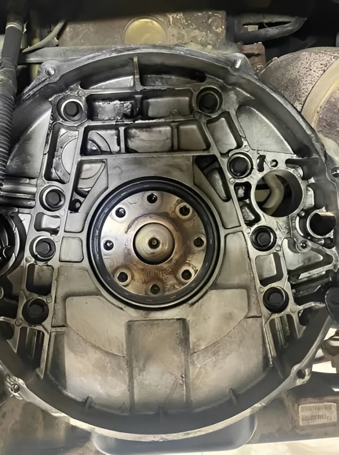 Mechanic holding a Cummins rear main crankshaft seal next to an oil pan gasket.